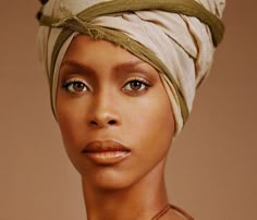 a woman with a turban on top of her head looking at the camera