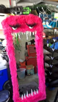 a pink monster mirror sitting on top of a table next to a pile of chairs