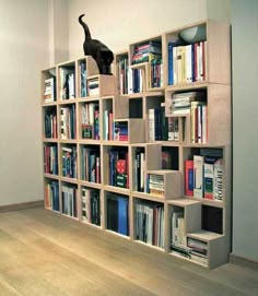 a bookshelf filled with lots of books and a cat statue on top of it