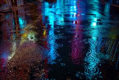 rain drops on the ground at night with street lights reflected in wet pavement and umbrellas