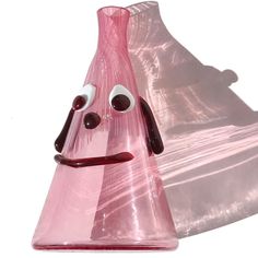 a pink glass vase with a face drawn on it