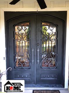 the front door to a home with wrought iron designs on it and a black rug