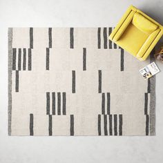 a yellow chair sitting on top of a white floor next to a rug with black stripes