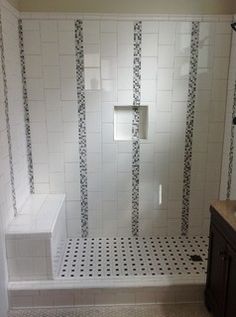 a bathroom with white and black tile on the shower wall, toilet and sink area