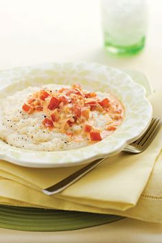 a white plate topped with oatmeal and bacon on top of a table