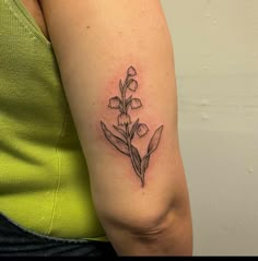 a woman's arm with a small flower tattoo on the left side of her arm