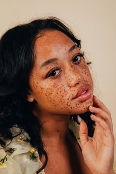 a woman with freckles on her face holding a cell phone to her ear