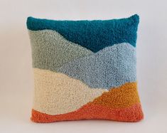 a decorative pillow with multicolored waves on it's back and sides, sitting on a white surface