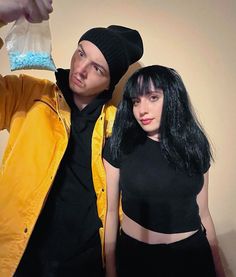 a man and woman posing for a photo with a toothbrush in their hand while wearing black hair