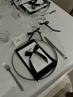 the table is set with black and white place settings, silverware, and napkins