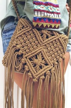 a woman holding a brown purse with fringes on it