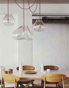 a dining room table with chairs and lights hanging from the ceiling