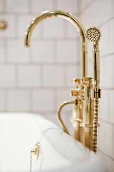 a gold faucet sitting next to a white bath tub