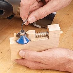 a person is working on something with wood and metal parts in their hands, including a blue light bulb