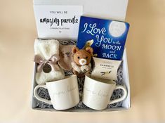 a gift box containing two mugs, a book and a stuffed animal