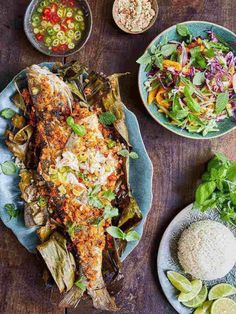 an overhead view of fish, salad and rice on a wooden table with bowls of vegetables