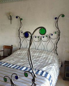 a metal bed frame with blue and green glass knobs on the headboard in a bedroom