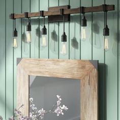 a mirror and some lights hanging on a wall next to a vase with flowers in it