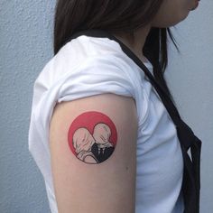 a woman with a small tattoo on her arm and shoulder, holding onto a red circle