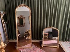 three gold mirrors sitting on top of a wooden table next to a mirror and rug