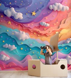 a boy is looking through a pair of binoculars in front of a colorful wall mural