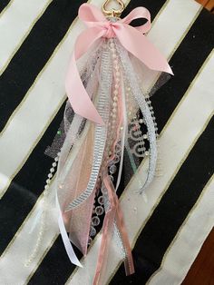 a pink ribbon hanging from the side of a black and white striped bag