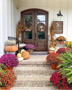 a front porch decorated for fall with flowers and pumpkins