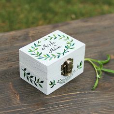 a small wooden box sitting on top of a wooden table next to a green plant