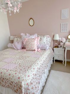 a bedroom with pink walls and white bedding has a chandelier hanging from the ceiling