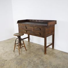 an old wooden desk with two stools next to it