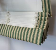 a green and white striped curtain hanging from the side of a window with tassels