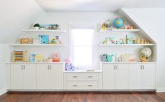 an empty room with white shelves and wooden floors