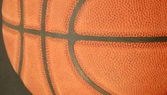 an orange and black basketball is shown in this close - up shot with the shadow of it's back