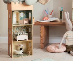 a wooden doll house with stuffed animals and toys on the floor in front of it