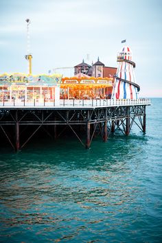 an amusement park sits on the water next to a pier