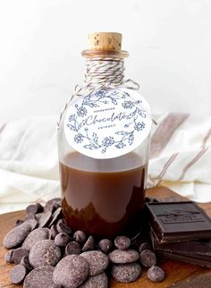 a bottle filled with liquid sitting on top of some rocks and chocolates next to it