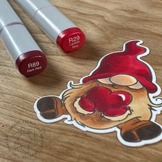 two red lipsticks sitting on top of a wooden table next to a sticker