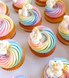 cupcakes decorated with rainbow icing and white flowers