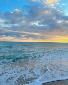 the ocean waves come in to shore as the sun is setting over the water and clouds