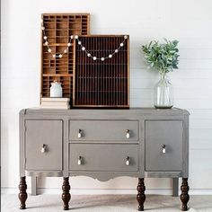 a gray dresser with drawers and a birdcage on top, next to a vase filled with flowers