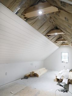 an unfinished attic with exposed wood beams and white walls that have been stripped off from the ceiling