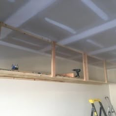 an unfinished room with white walls and wooden beams on the ceiling is being worked on