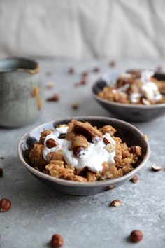 two bowls filled with granola, nuts and yogurt on top of a table