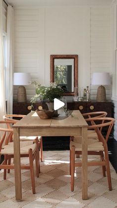 a dining room table with chairs and a mirror on the wall in front of it