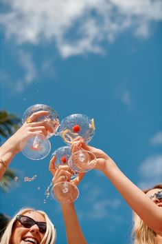 three women are holding up wine glasses in the air