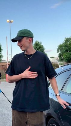 a man standing in front of a car talking to another man with his hand on his hip