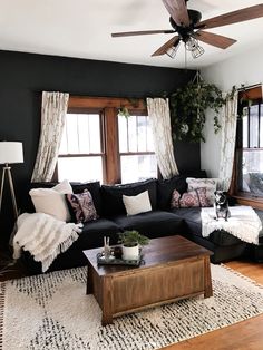 a living room with black couches and white pillows on top of the rugs