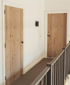 an empty room with two wooden doors on the wall and a metal railing in front of it