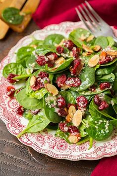 spinach salad with cranberries and almonds on a red and white plate