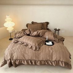 the bed is made with brown comforters and pillows, along with a white lamp